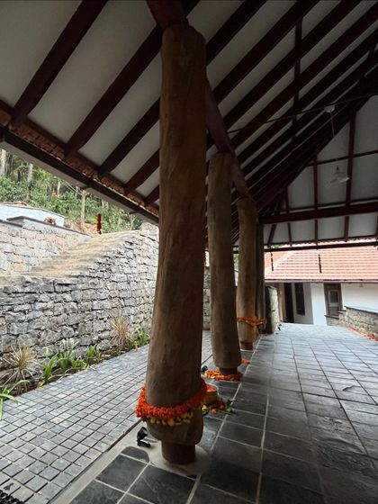 The powerful presence of reclaimed timber pillars on the veranda of the Coorg house, decorated with marigolds for the housewarming ceremony.