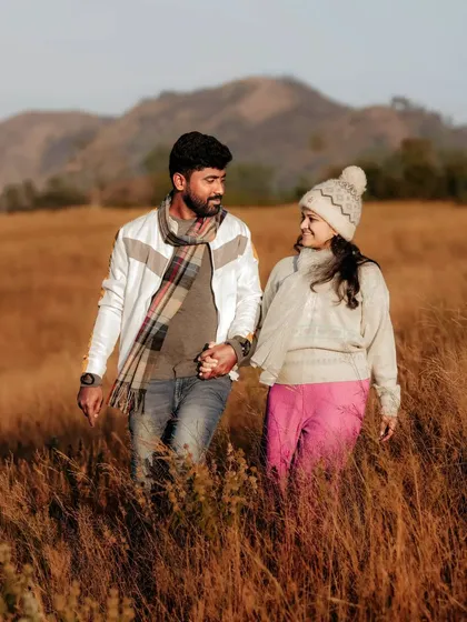 Walking hand-in-hand through a field of golden grass, this couple's pre-wedding photo captures a sense of journey and togetherness against a beautiful mountain backdrop.