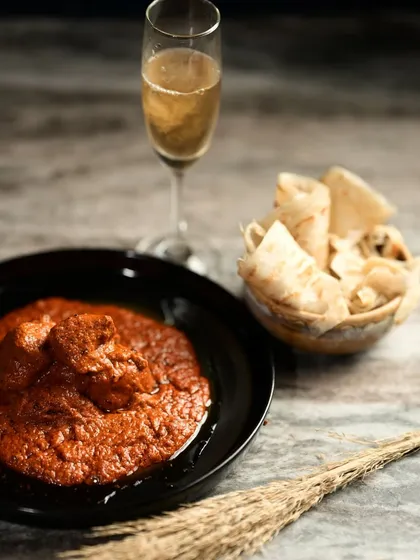 The Angara Murg Korma presented as a celebratory meal, paired with a glass of sparkling drink, perfect for a special dinner.