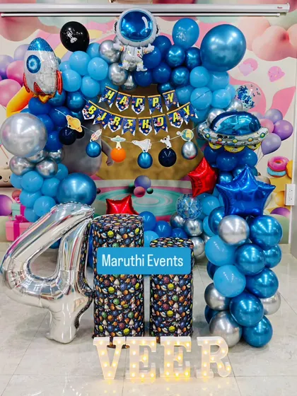 An out-of-this-world astronaut theme for a 4th birthday. This party features a balloon arch with rocket and planet elements, astronaut figures, and custom-printed space-themed plinths.