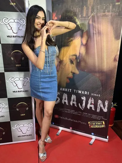 Posing with the poster for her new song "Saajan". This full-length shot shows how the complete look comes together for a promotional event.