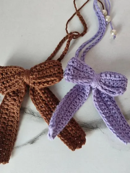 Another angle of the lavender and brown crochet bows, showing the delicate pearl accent and the neatness of the stitches.