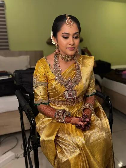My beautiful bride Vani looking flawless for her Muhurtham in Dharapuram. She is adorned in a stunning gold Kanjeevaram saree with intricate antique jewellery, and her makeup features a soft smoky eye and a neutral lip.