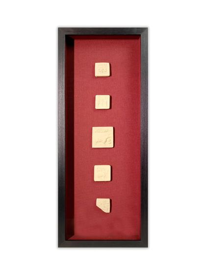A single, tall shadow box designed to display a series of small, ancient tablets. This vertical arrangement creates a narrative flow, drawing the eye from one piece to the next, all protected behind museum glass.