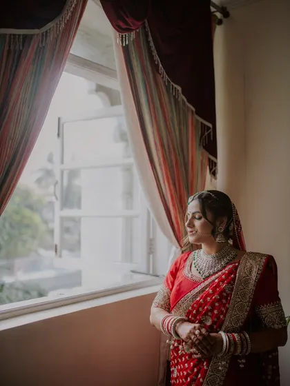 A serene and beautiful portrait of the bride looking out the window, lost in thought before her wedding.