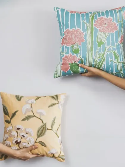 A study in contrast and harmony. Here, we pair a hand-embroidered floral cushion in soft yellow with a modern, block-printed design in cool blue and pink, showing how different styles can beautifully complement each other.