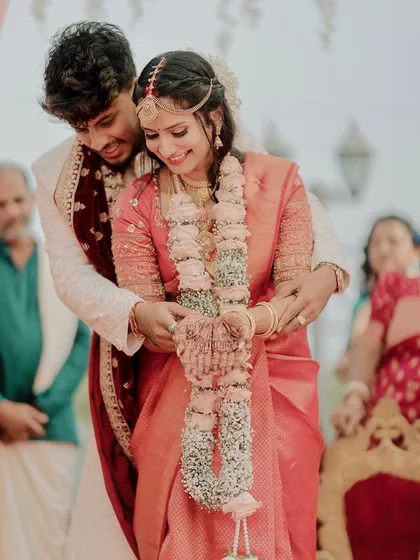 The groom helps his bride with her garland, a small, tender gesture of care during the wedding ceremony.