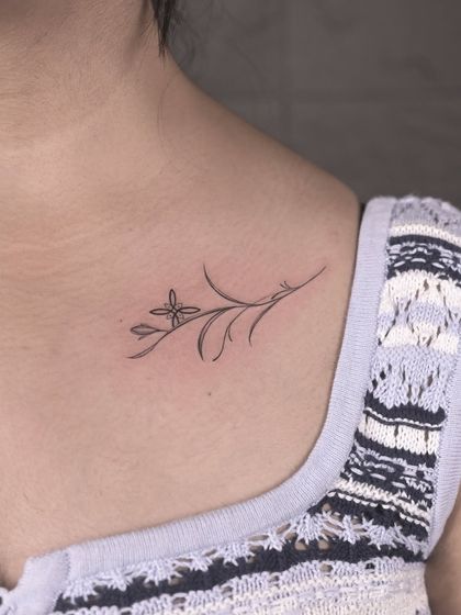 A delicate floral sprig placed perfectly on the collarbone. This is a great example of a minimalist tattoo that is both subtle and beautiful, using clean lines to create an elegant piece.