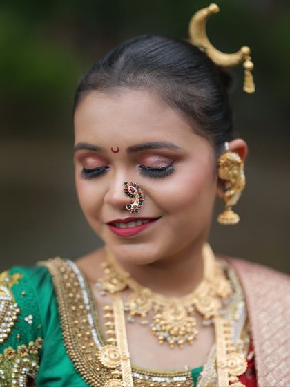 The serene expression of a bride, highlighting the detailed makeup and the traditional Maharashtrian nath.