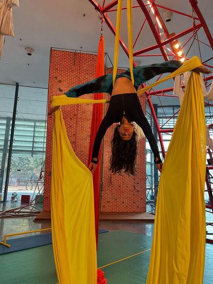 A student performs an inverted split, holding the yellow silks for support. This pose is a fantastic goal for building flexibility and upper body strength.