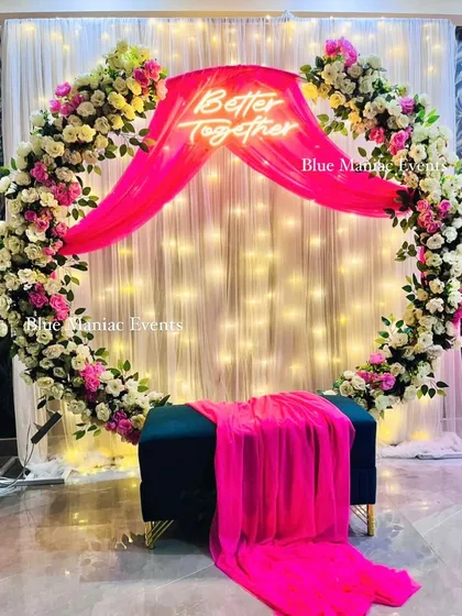 A full view of the Roka ceremony decoration with a pink and white floral ring. The deep teal bench provides a beautiful color contrast, making the whole setup pop.