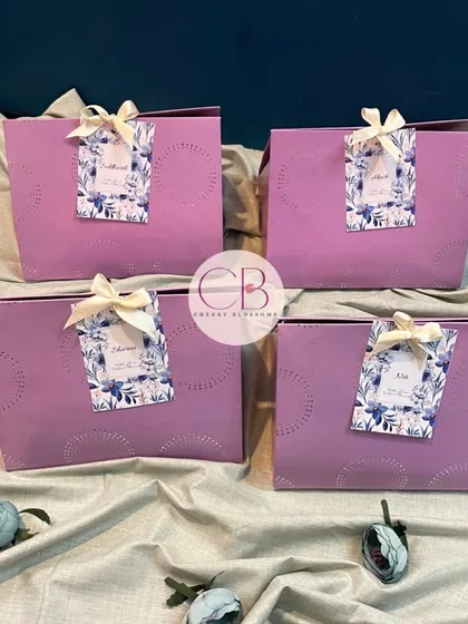 A set of our elegant pastel purple gift bags used for wedding favours. Each bag is personalised with a custom floral tag bearing the guest's name for a special touch.