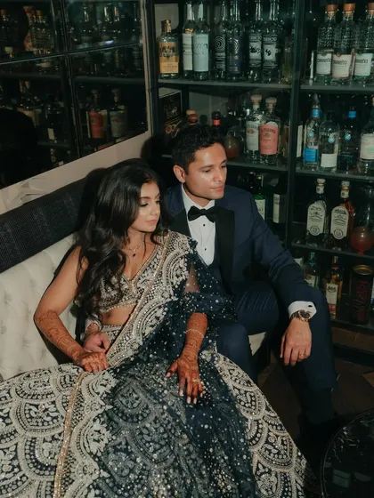 A moody and stylish portrait of the couple in a bar. The dark, intimate setting and their formal attire create a sophisticated, cinematic feel for their reception.