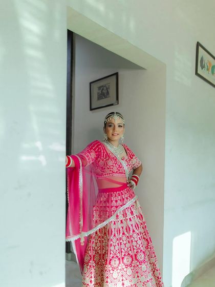 The bride looking radiant in her bright pink lehenga. This portrait captures her elegance and the joy of her wedding day.