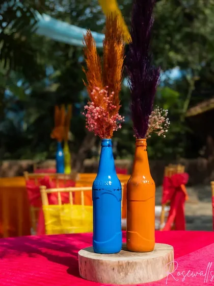 A close-up of our DIY-style centerpieces, using painted bottles with colorful dried pampas grass, which perfectly suits the fun, carnival vibe.