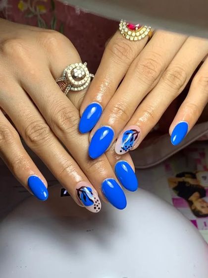 A bold set of royal blue nails with abstract butterfly wing accents.