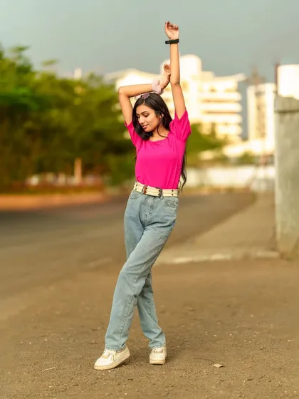 A joyful and energetic pose, with the model's arms raised, capturing a free-spirited moment during the outdoor shoot.