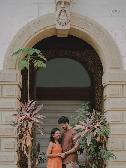 Framed by a beautiful stone archway and lush plants, Nikit and Anusha share a gentle moment. This shot highlights our skill in finding unique architectural frames within a bustling city.
