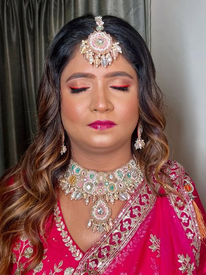 A close-up of the eye makeup, featuring a bold red-pink liner that makes a statement.