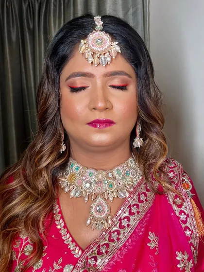 A close-up of the eye makeup, featuring a bold red-pink liner that makes a statement.
