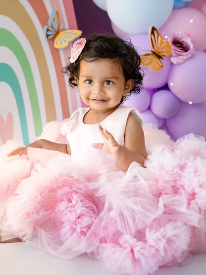 A close-up of the birthday girl in her stunning pink dress, surrounded by the colorful butterfly and rainbow backdrop.