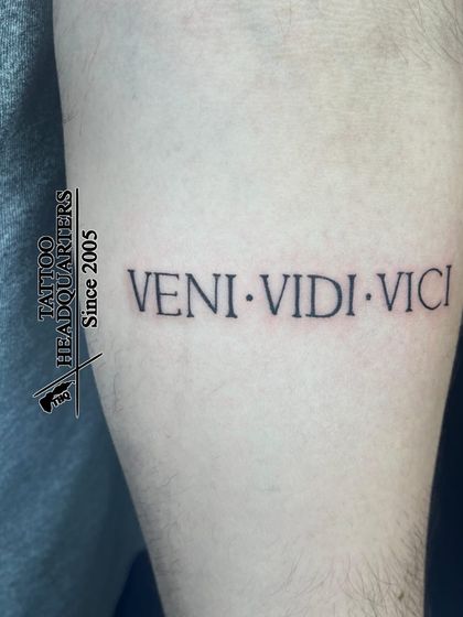 The famous Latin phrase "VENI. VIDI. VICI" ("I came, I saw, I conquered") tattooed in a clean, classic font on the forearm.