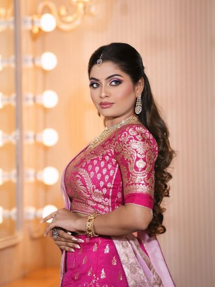 A side profile of the pink and purple look, showing the hairstyle and the way the makeup complements the traditional pink saree.