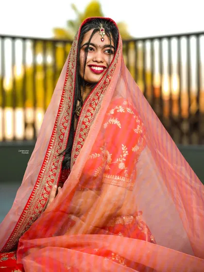 A candid, happy portrait of the bride, her face framed by the sheer dupatta, capturing a moment of pure joy.