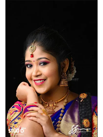 A close-up portrait of the South Indian bridal makeup. This shot highlights the radiant skin, the pop of color on the eyes and lips, and the traditional bindi and maang tikka.