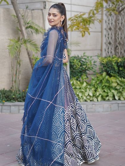 A contemporary navy blue and white lehenga with a bold geometric pattern. The ruffled dupatta adds a touch of modern flair, making it a great choice for a sangeet or cocktail party.
