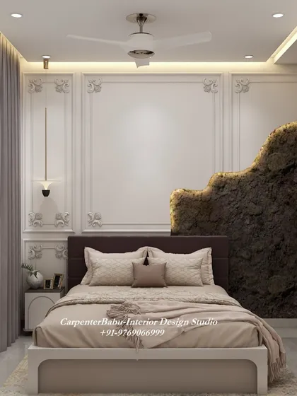 This bedroom has a dramatic and luxurious feel, with a feature wall that combines classic molding with a raw, textured stone-like element.