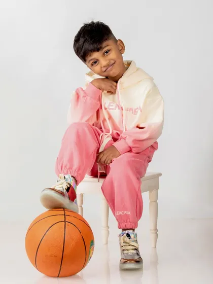 A cool, modern portrait of the 5-year-old in a pink and white tracksuit, posing with a basketball.