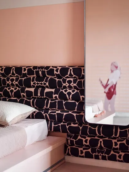 In the second children's room, we used a bold, graphic fabric for the custom headboard. The reflection in the mirror shows a hint of a guitar, a nod to the child's passion for music.