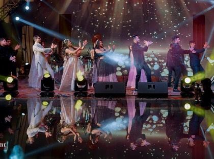 A fun, energetic 'jugalbandi' between the bride's side and the groom's side. The reflection on the stage makes it look even more grand.