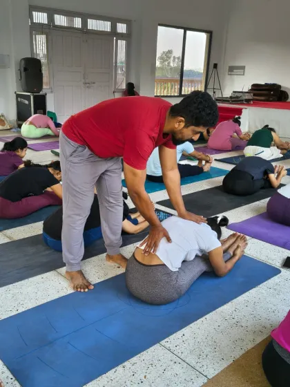 We believe in providing personal guidance on this journey. This is a moment from our Rishikesh retreat where I am offering a hands-on adjustment in a forward bend, ensuring safe alignment and a deeper release for the practitioner.