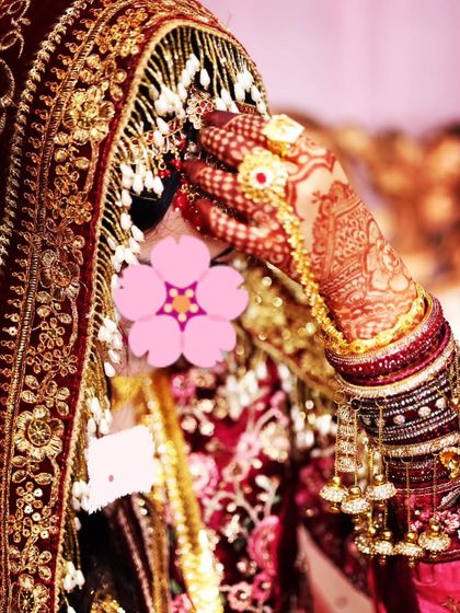 A shy bride pose, with her hand elegantly covering her face, highlighting the intricate henna design.