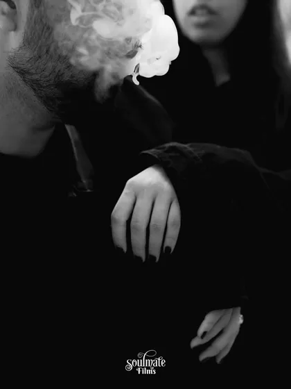 A moody and atmospheric black and white shot. The smoke and the close crop on their hands and embrace create an edgy, intimate, and mysterious vibe.