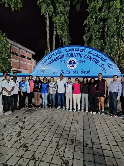 Our home base. The women's water polo team stands proudly with their coaches and officials in front of the Basavanagudi Aquatic Centre. This is where champions are built, through rigorous training, expert guidance, and unwavering team support.