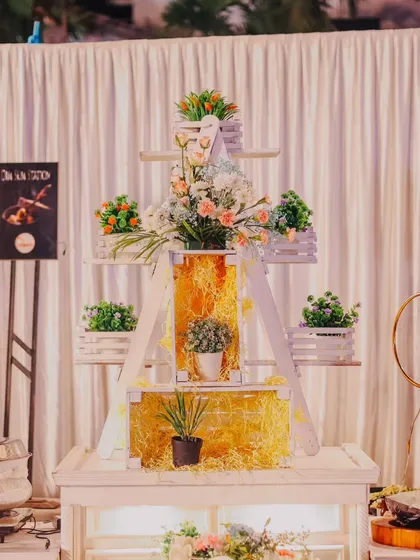 A decorative food station setup featuring a white tiered shelf adorned with plants and rustic elements. This shows how I integrate decor directly into the buffet presentation.