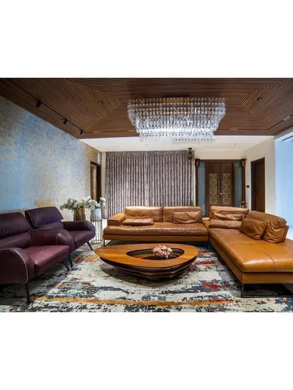 I often mix textures to create a statement. In this living room, a textured blue accent wall and a grand crystal jhoomar contrast beautifully with the warm leather sofa and wooden ceiling, creating a space that feels both grand and grounded.