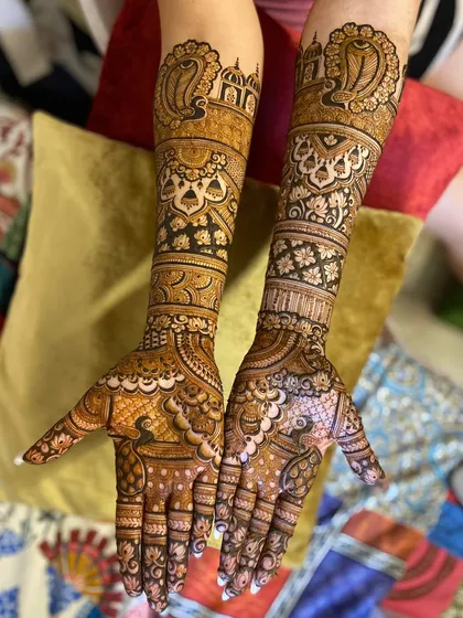 This bridal design features classic motifs like peacocks and architectural domes. The patterns are dense and symmetrical, creating a timeless and elegant look for the bride.