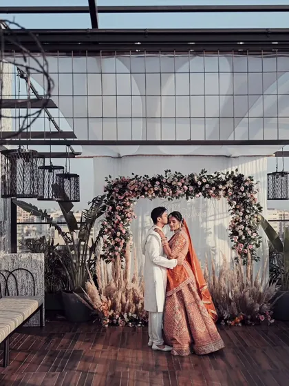 A stunning wide-angle portrait of the couple on a rooftop venue overlooking the city. This shot captures both their intimate moment and the grand scale of their urban wedding.