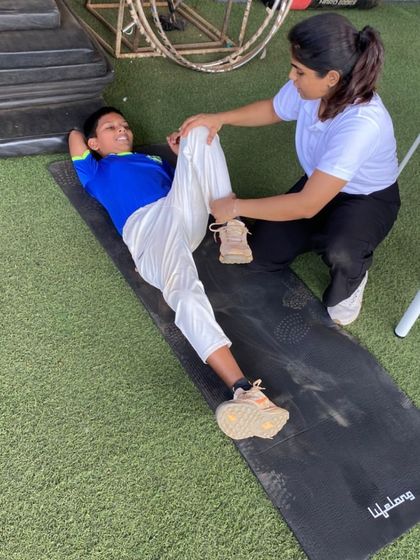 A trainer assists a player with a deep stretch on a mat. Proper stretching is essential for flexibility, performance, and preventing muscle injuries.