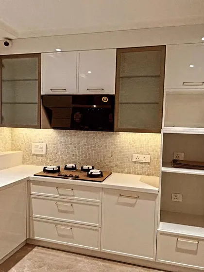 A detailed shot of the cooking zone. The four-burner hob is set against a beautiful mosaic tile backsplash, with open shelving on the side for easy access to everyday items.
