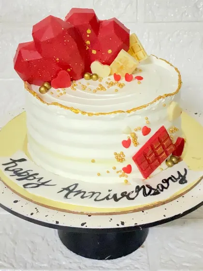 When two hearts meet. This butterscotch anniversary cake is topped with geometric chocolate hearts and decorated with edible gold dust for a modern romantic feel.