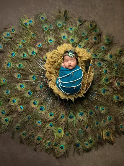 Creating a touch of magic with my popular Krishna-themed newborn session. This wide-angle shot shows the beautiful setup with a full display of peacock feathers, turning your baby's first portraits into a divine work of art.