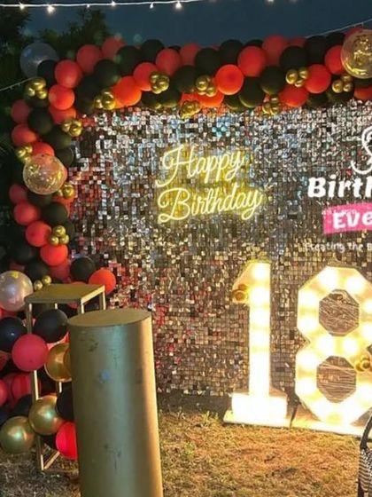 An 18th birthday setup that makes a statement. We used a silver sequin wall with a red, black, and gold balloon arch and matching marquee numbers for a bold and dramatic look.