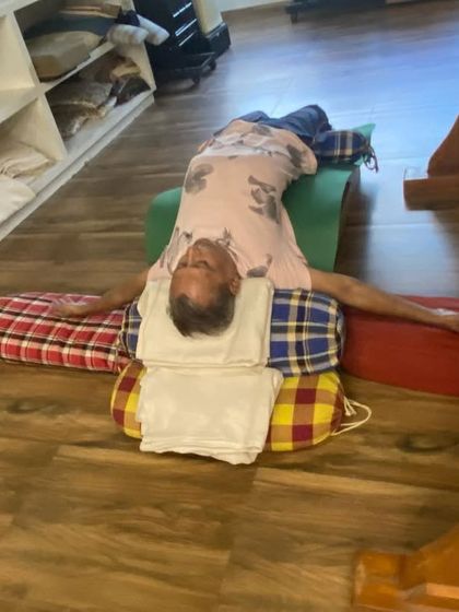 A restorative setup on the floor with multiple bolsters and blankets supporting the head, neck, and back. This allows for complete surrender and release.