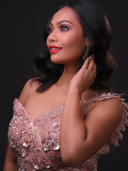 The side view shows the soft, romantic hairstyle and the feathered details on the gown.