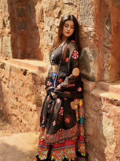A full-length shot of the multi-colored lehenga against a rustic stone wall.